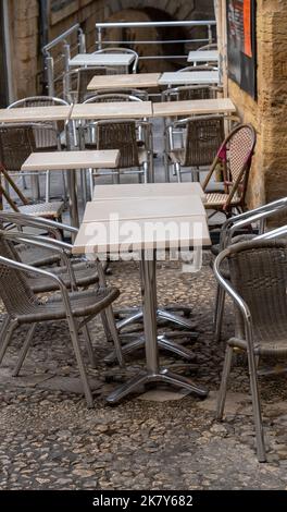 Tavoli e sedie in una strada acciottolata fuori di un ristorante a Sarlat-la-Caneda una città medievale 14th ° secolo conservato in Dordogna Francia Foto Stock