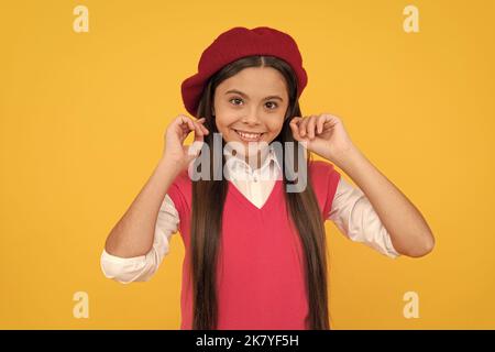 felice teen ragazza scuola in beret francese su sfondo giallo, bellezza Foto Stock