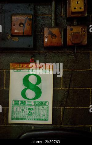 Dettaglio di un calendario, prese di corrente e interruttori macchiati da anni di fumo di incenso, nel tempio di Tin Hau, Yau ma Tei, Kowloon, Hong Kong Foto Stock