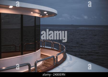 Una vista in basso di una parte di un ponte safari vicino alla prua della barca o della sua poppa, con un passaggio recintato con una recinzione cromata e un gla specchiato Foto Stock