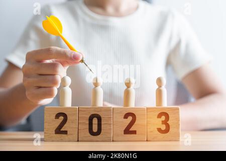 Mano che tiene dardo sopra la gente e 2023 anno blocks.goal, piano, azione, obiettivo, strategia, Leadership, Capodanno e concetto di marketing Foto Stock