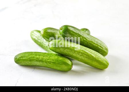 Mini cetrioli su marmo bianco, pronti per cucinare e mangiare Foto Stock