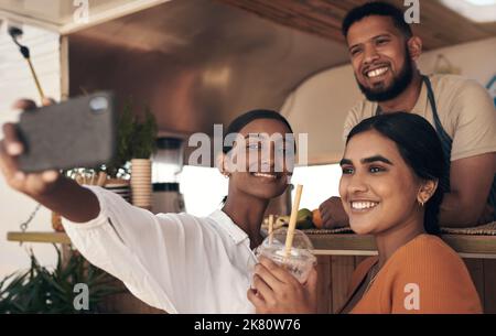 Ora mi dia un grande sorriso. Due amici scattano selfie mentre bevono frullati. Foto Stock