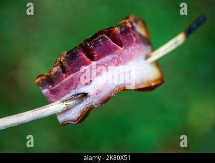 Pancetta di maiale cruda sullo spiedino all'aperto Foto Stock