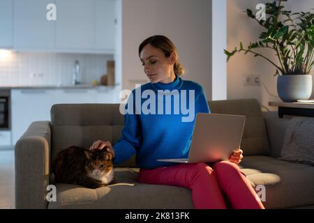 Giovane donna guarda con bella espressione a gatto domestico e ama trascorrere il tempo con gli animali Foto Stock
