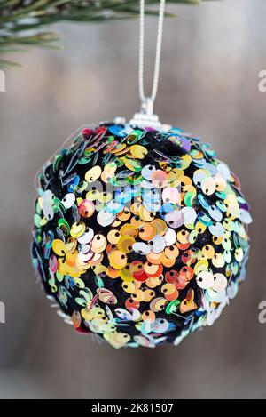Sospensione multicolore glitter palla di Natale su abete rosso e su sfondo sfocato Foto Stock