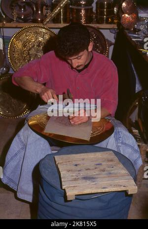 Siria: Artigiano di brassware nel grande bazar antico, Aleppo (1997). Il Grande Bazar di Aleppo (in arabo, suq o suq) fu ricostruito prima dai Mamelucchi egiziani che scacciarono i Mongoli, e poi, dopo il 1516, dai Turchi che incorporarono Aleppo nell'Impero Ottomano. Durante la guerra civile siriana, iniziata nel 2011, i suq storici di Aleppo subirono gravi danni. Aleppo, la seconda città della Siria è forse il più lungo insediamento continuamente abitato del mondo. Il suo nome arabo, Halab, è menzionato nei testi semitici del terzo millennio a.C.. Foto Stock