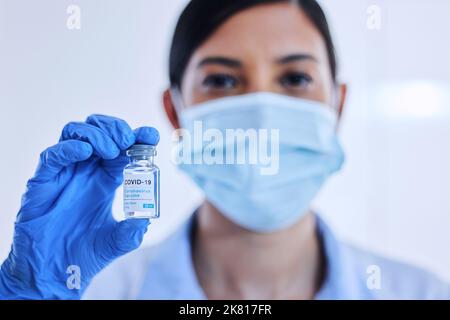 Questo ti guarirà. Uno scienziato femminile irriconoscibile che tiene in mano una bottiglia del vaccino Covid 19. Foto Stock