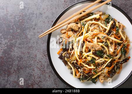 Japchae coreano Stir-fritto tagliatelle di vetro e verdure primo piano sul piatto sul tavolo. Vista orizzontale dall'alto Foto Stock