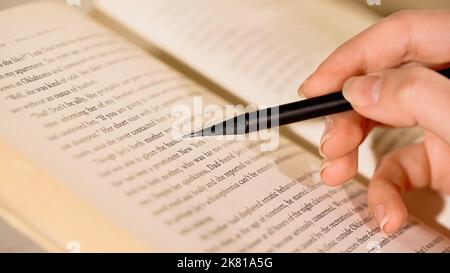 Vista ritagliata della donna che tiene la matita vicino al libro, immagine di scorta Foto Stock