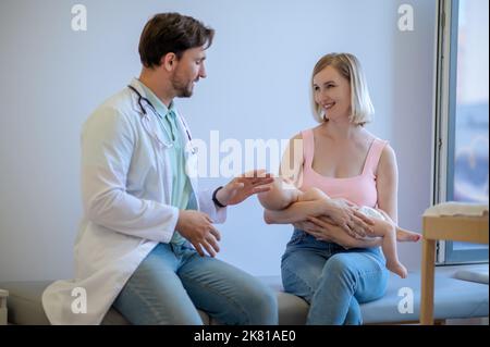 Medico pediatrico che riceve i pazienti nel suo ufficio Foto Stock