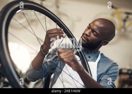 Vedete una bicicletta, vedo un'erba più verde, un giovane che fissa una ruota in un negozio di riparazione di biciclette. Foto Stock