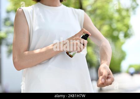 Donna giapponese che usa repellente per insetti Foto Stock