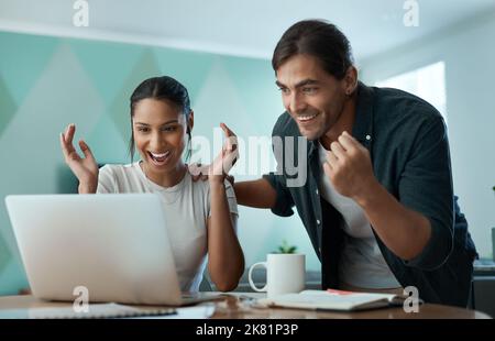 Raggiungere i nostri obiettivi è sempre fantastico: Una giovane coppia che usa un notebook a casa. Foto Stock
