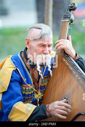 Un Kobzar non identificato che canta al suo proprio accompagnamento su uno strumento bandura in via Khreshchatyk a Kiev, Ucraina Foto Stock