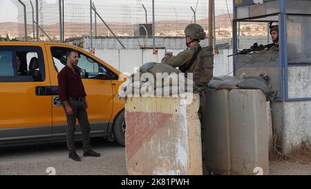 I soldati israeliani stanno in guardia dietro blocchi di cemento mentre controllano le carte d'identità dei civili palestinesi nel checkpoint militare di Beit Furik il 19 ottobre 2022 situato all'entrata orientale di Nablus, in Cisgiordania. Le forze israeliane hanno imposto un continuo blocco sulla zona intorno a Nablus, tra le tensioni più forti in Cisgiordania che limitano il movimento di circa 420.000 palestinesi. Foto Stock