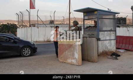 I soldati israeliani stanno in guardia dietro blocchi di cemento mentre controllano le carte d'identità dei civili palestinesi nel checkpoint militare di Beit Furik il 19 ottobre 2022 situato all'entrata orientale di Nablus, in Cisgiordania. Le forze israeliane hanno imposto un continuo blocco sulla zona intorno a Nablus, tra le tensioni più forti in Cisgiordania che limitano il movimento di circa 420.000 palestinesi. Foto Stock