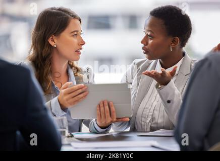 Due giovani donne d'affari che si riuniscono in ufficio e che discutono mentre usano un tablet digitale? Foto Stock