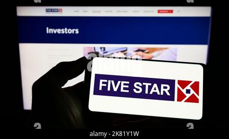 Persona che tiene il cellulare con il logo della società Five-Star Business Finance Limited sullo schermo di fronte al sito web aziendale. Messa a fuoco sul display del telefono. Foto Stock