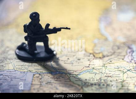 Giocattolo militare armato in miniatura con pistola sulla mappa, simbolo del conflitto di guerra Foto Stock