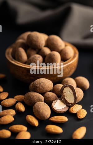 Mandorle in cioccolato ricoperte di cacao in ciotola su un tavolo scuro. Foto Stock