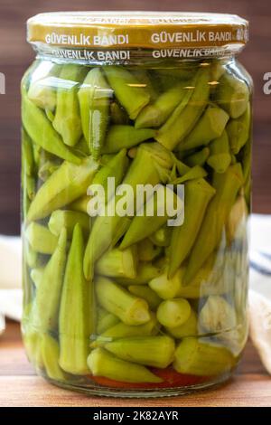 Okra in scatola in vaso di vetro su sfondo di legno Foto Stock