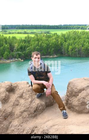 Un escursionista stanco si sedette in pietra sulla cima di una montagna. Foto Stock