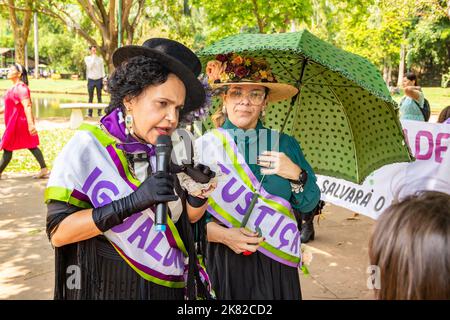 Goiânia, Goias, Brasile – 12 ottobre 2022: Una donna, vestita a suffragetta, che parla nel microfono e un'altra donna che tiene un ombrello. Foto Stock