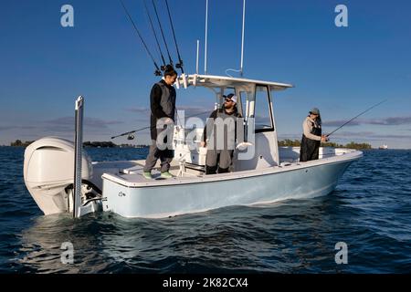 Tre persone che pescano da una barca console centrale. Foto Stock