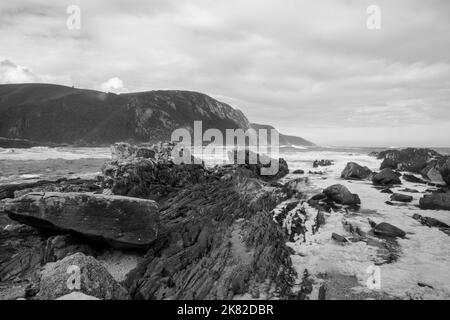 Onde che si infrangono contro rocce che si infrangono sulla costa Foto Stock