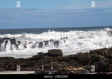 Onde che si infrangono contro rocce che si infrangono sulla costa Foto Stock