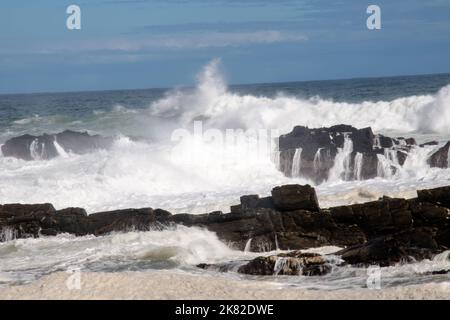 Onde che si infrangono contro rocce che si infrangono sulla costa Foto Stock