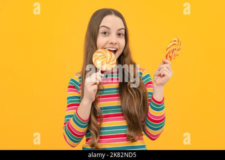 Ragazza adolescente con caramelle al caramello sui bastoni, dolce dipendenza da zucchero. Bambino con lollipops. Foto Stock