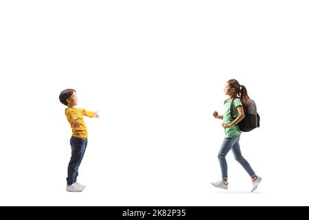 Foto a profilo completo di una scolaretta che corre verso un ragazzino con braccia larghe isolate su sfondo bianco Foto Stock