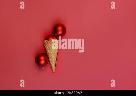 Piatto posare alternative palle di Natale gelato in cono waffle su sfondo rosso. Un angolo arrotolato. Concetto di festa di festa di inverno, composizione di festa di vista dall'alto. Foto Stock
