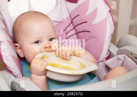 bambina che mangia con il cucchiaio in cucina Foto Stock