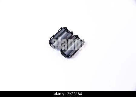 Primo piano di un induttore a cordone di ferrite. Un elemento elettrico che sopprime il rumore elettronico ad alta frequenza nei circuiti elettronici. Su bianco isolato Foto Stock