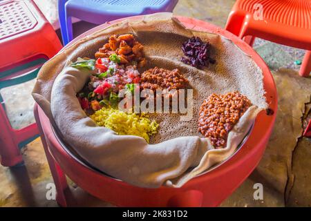 Pasto tipico in Etiopia - Beyainatu. Mearing un po' di tutto. Mix di verdure e stufati su injera flatbread. Foto Stock