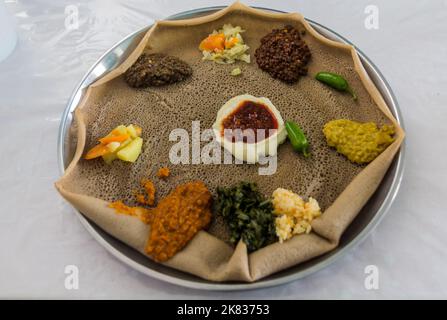 Pasto tipico in Etiopia - Beyainatu. Mearing un po' di tutto. Mix di verdure e stufati su injera flatbread. Foto Stock