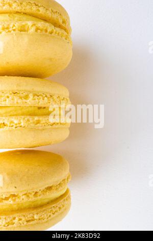 Tre macaron francesi al limone giallo su fondo bianco Foto Stock