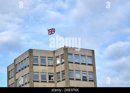 Bandiera britannica su un edificio con sfondo nuvoloso. Foto Stock