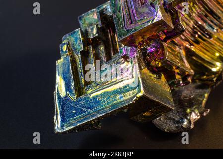 Bismuto bi primo piano su superficie nera.interessante colore e forma cristallo. Cristallo metallico Foto Stock