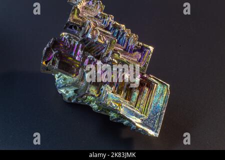 Bismuto bi primo piano su superficie nera.interessante colore e forma cristallo. Cristallo metallico Foto Stock