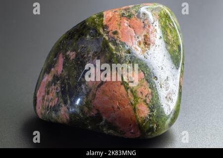 Macro tumbled Unakite Jasper isolato su sfondo grigio Foto Stock