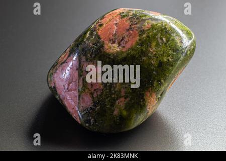 Macro tumbled Unakite Jasper isolato su sfondo grigio Foto Stock