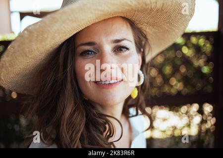 Ritratto di giovane donna in camicia bianca con cappello nel patio della guest house hotel. Foto Stock