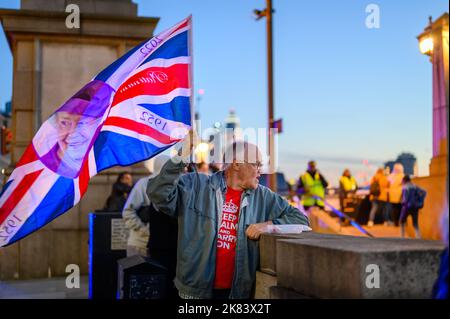 Londra - 17 settembre 2022: L'uomo tiene la bandiera di Union Jack con il volto della Regina su di essa nella luce della prima sera Foto Stock