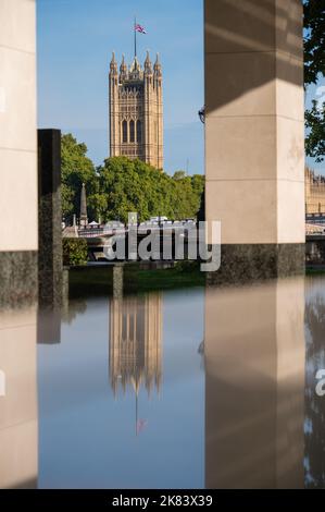 Londra - 18 settembre 2022: La Victoria Tower delle Case del Parlamento e il suo riflesso in superficie marmorea. Followin mezzo albero volante Union Jack Foto Stock