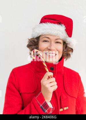 Donna riccia con canna da zucchero a righe. Bella femmina con frusta di liquirizia di Natale. Foto Stock