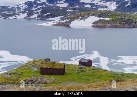 piccola casa norvegese e capannone di fronte ad un lago con galleggianti di ghiaccio Foto Stock